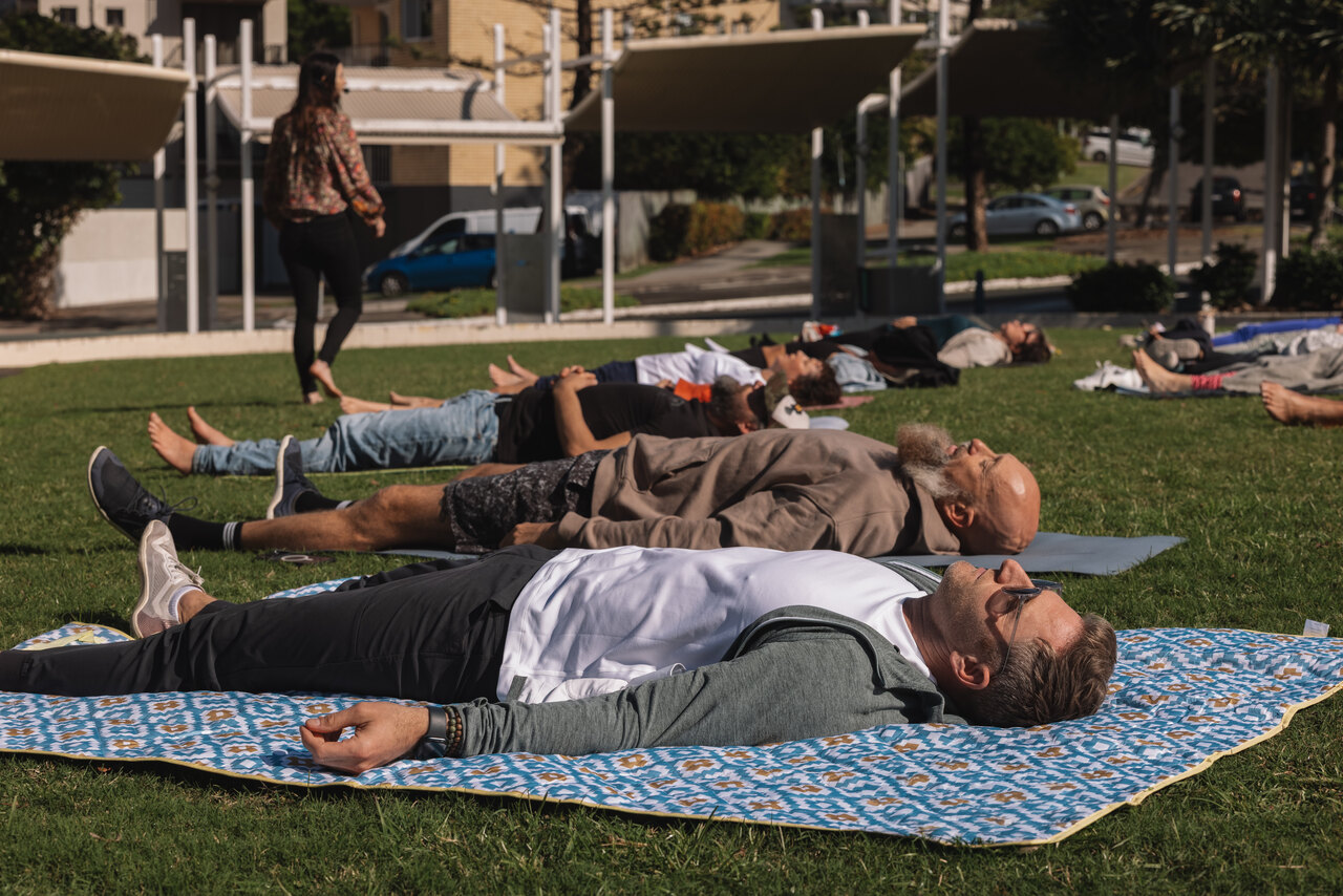 Participants resting on mats and blankets on the grass during an outdoor session